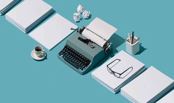 copywriting typewriter with paper, glasses, coffee and pens